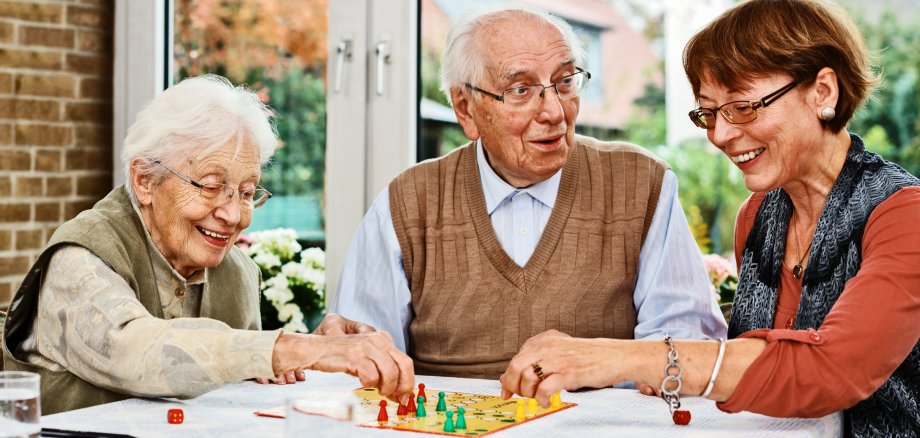 Elderly couple and daughter, playing board game