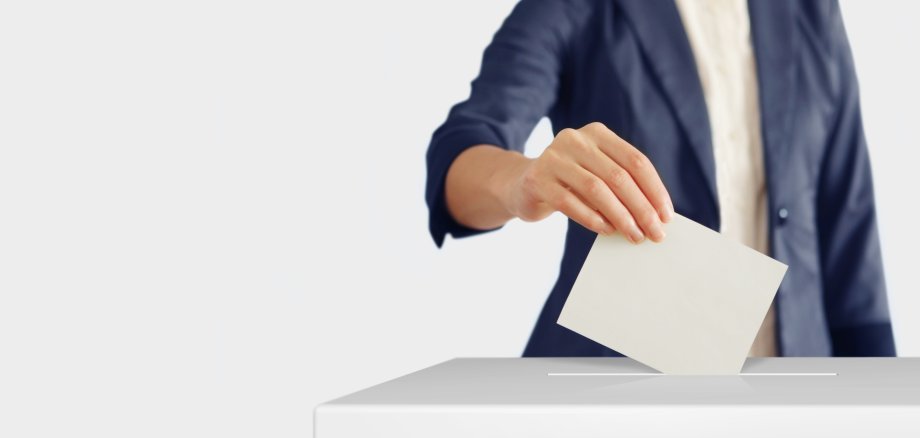 Voting. Woman putting a ballot into a voting box.